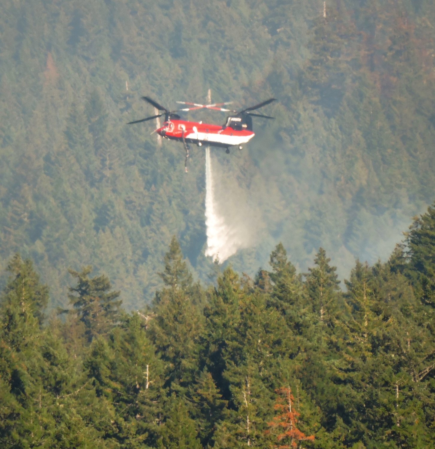 A helicopter drops water on the Goat Rocks fire on Monday.
